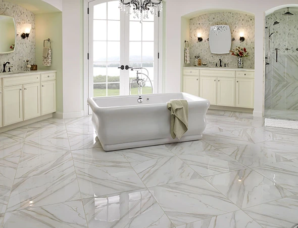 Luxury master bathroom featuring a white clawfoot bathtub and professionally installed marble-patterned floor tiles in a chevron layout.