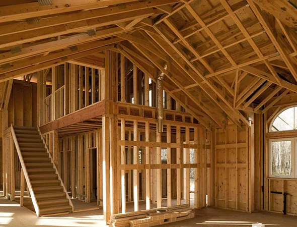 Custom wood house framing and interior structural beams for a residential construction project by contractors in Essex, VT.