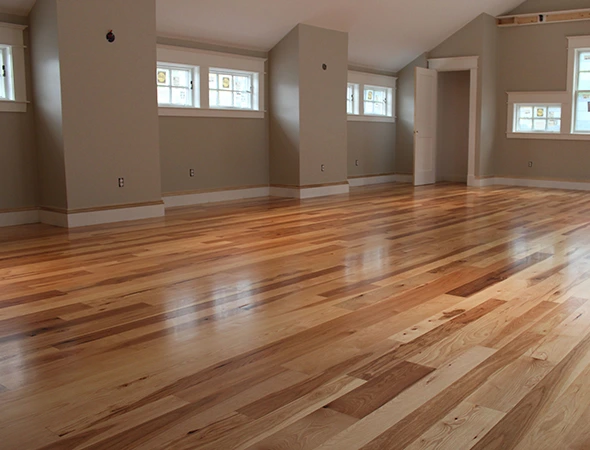 Professional hardwood flooring installation with high-gloss finish in a modern living room featuring neutral walls and natural light.