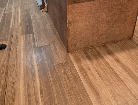 Close-up of a professional luxury vinyl plank flooring installation around a kitchen island in Montpelier, VT.