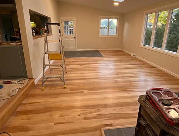 Wide view of a luxury engineered hardwood floor installation in progress in a bright Stowe, VT home.