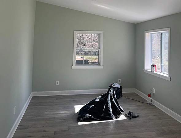Interior residential construction site in Montpelier, VT, showing exposed wall framing, concrete floors, and protective plastic sheeting.