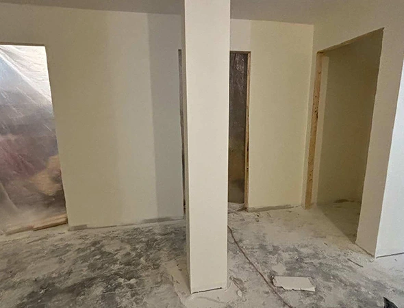 Interior home renovation under construction in Montpelier, VT, showing new drywall installation, structural support beams, and protective plastic sheeting.